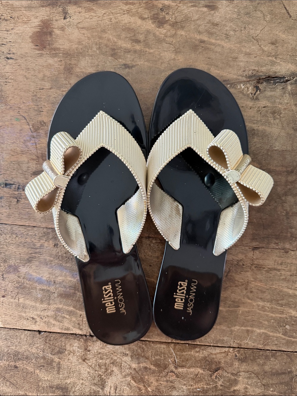 Melissa JasonWu black jelly sandals with gold bow strap.